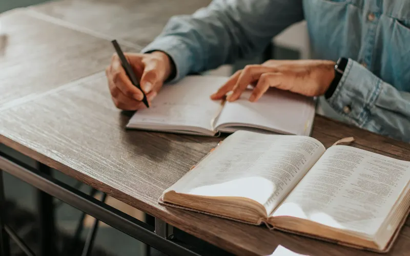 A man writing notes beside his open Bible