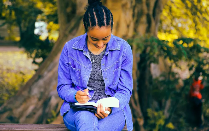 A woman journaling under a tree in golden light