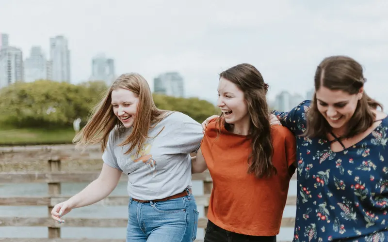 Three women walking arm in arm and laughing