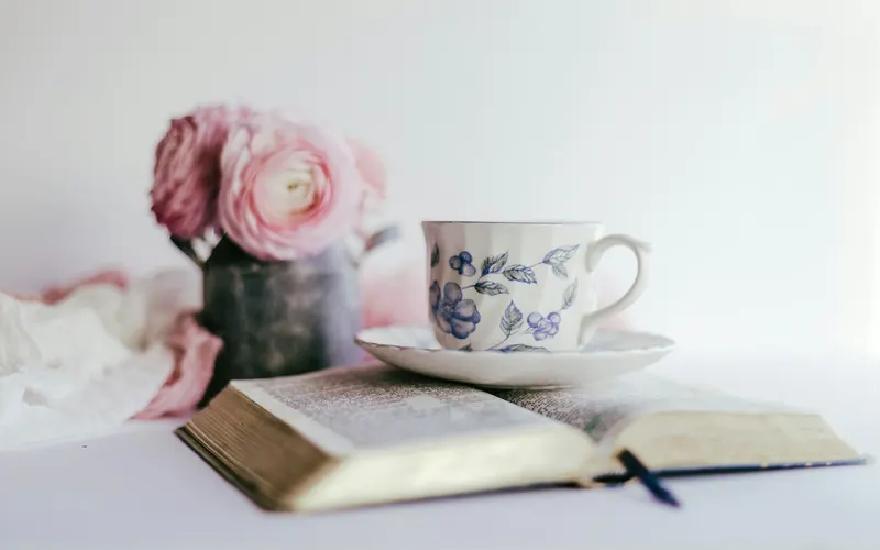 An open Bible with a teacup and pink ranunculus