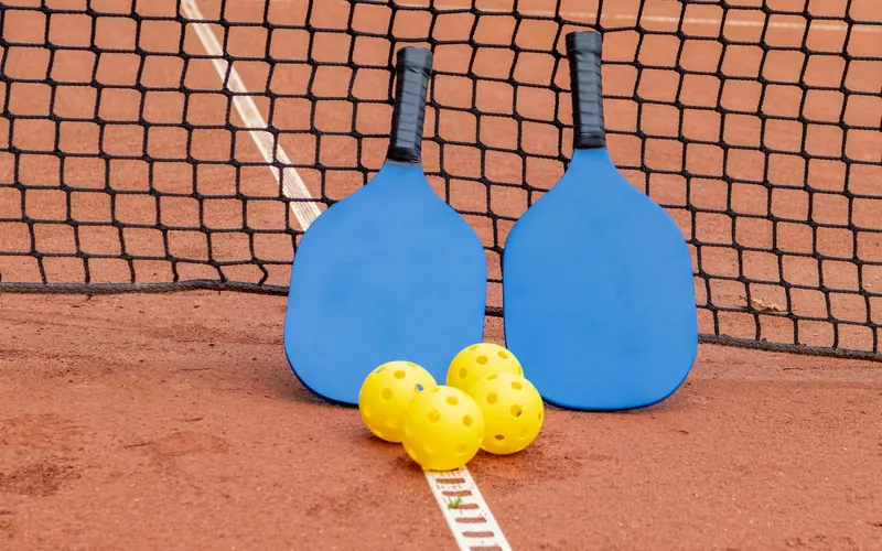 Two pickleball paddles and balls at the net