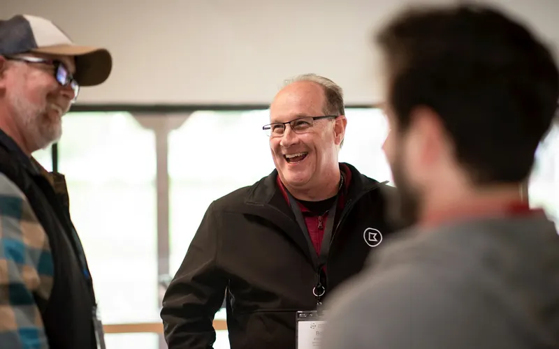 Three men laughing together in a sunlit room