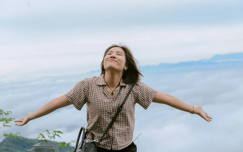 A woman with her arms spread wide above the clouds