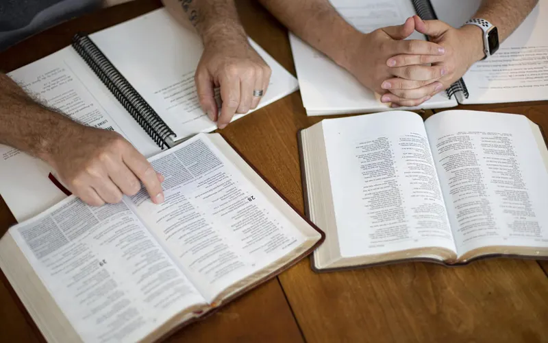 Men studying together around a table with open Bibles and spiral workbooks