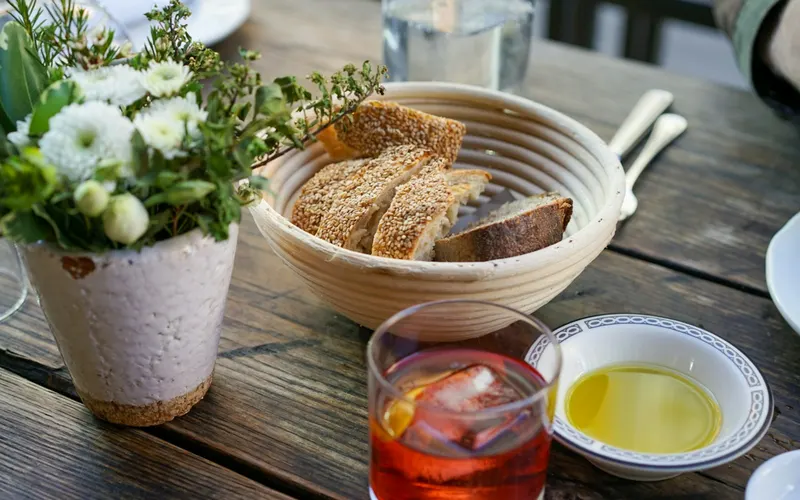 A basket of bread on a set table with flowers