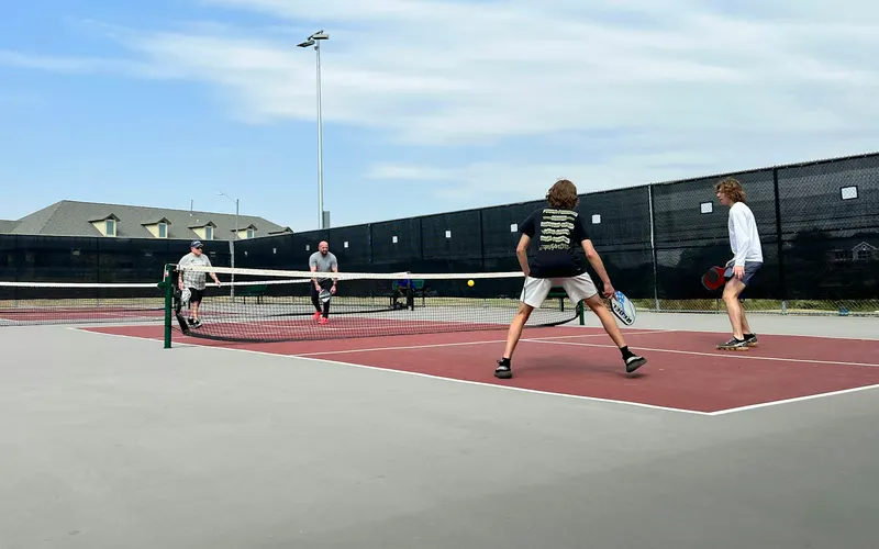 Four people playing pickleball on outdoor courts