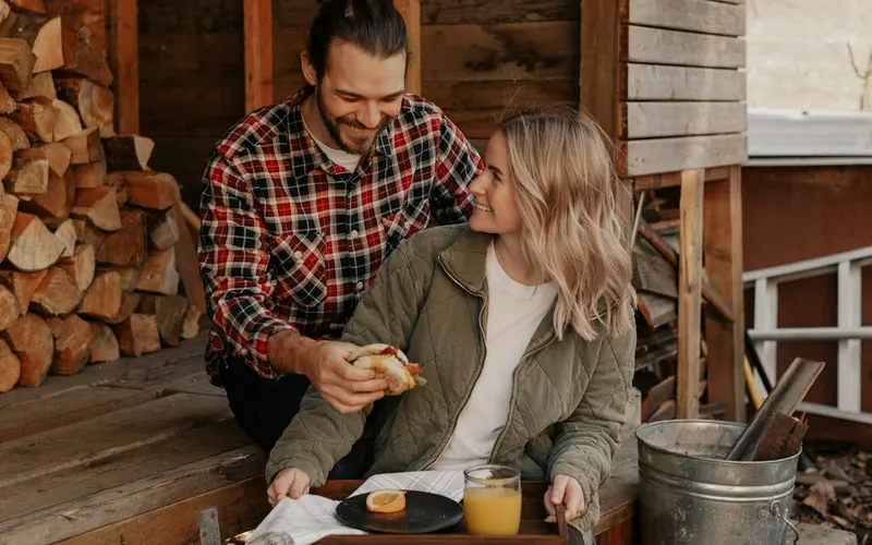 A young couple sharing breakfast on a porch bench