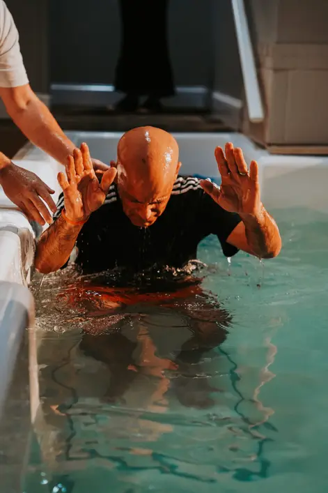 A new believer raising his hands in the baptism pool