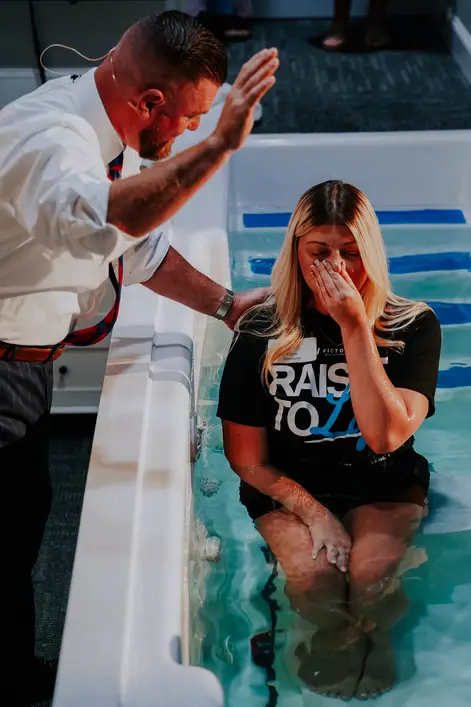 A woman being baptized in the baptistry at Victory