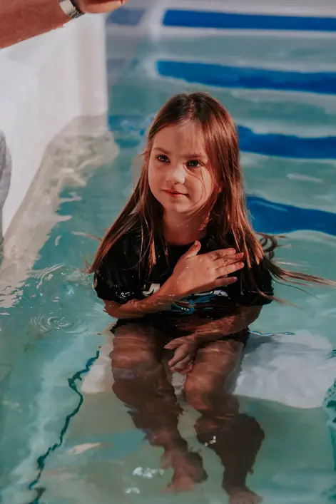A young girl smiling in the baptistry, her hair still wet from her baptism