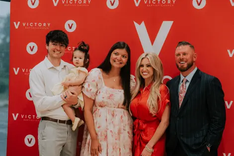 A family of five together at the Victory photo wall