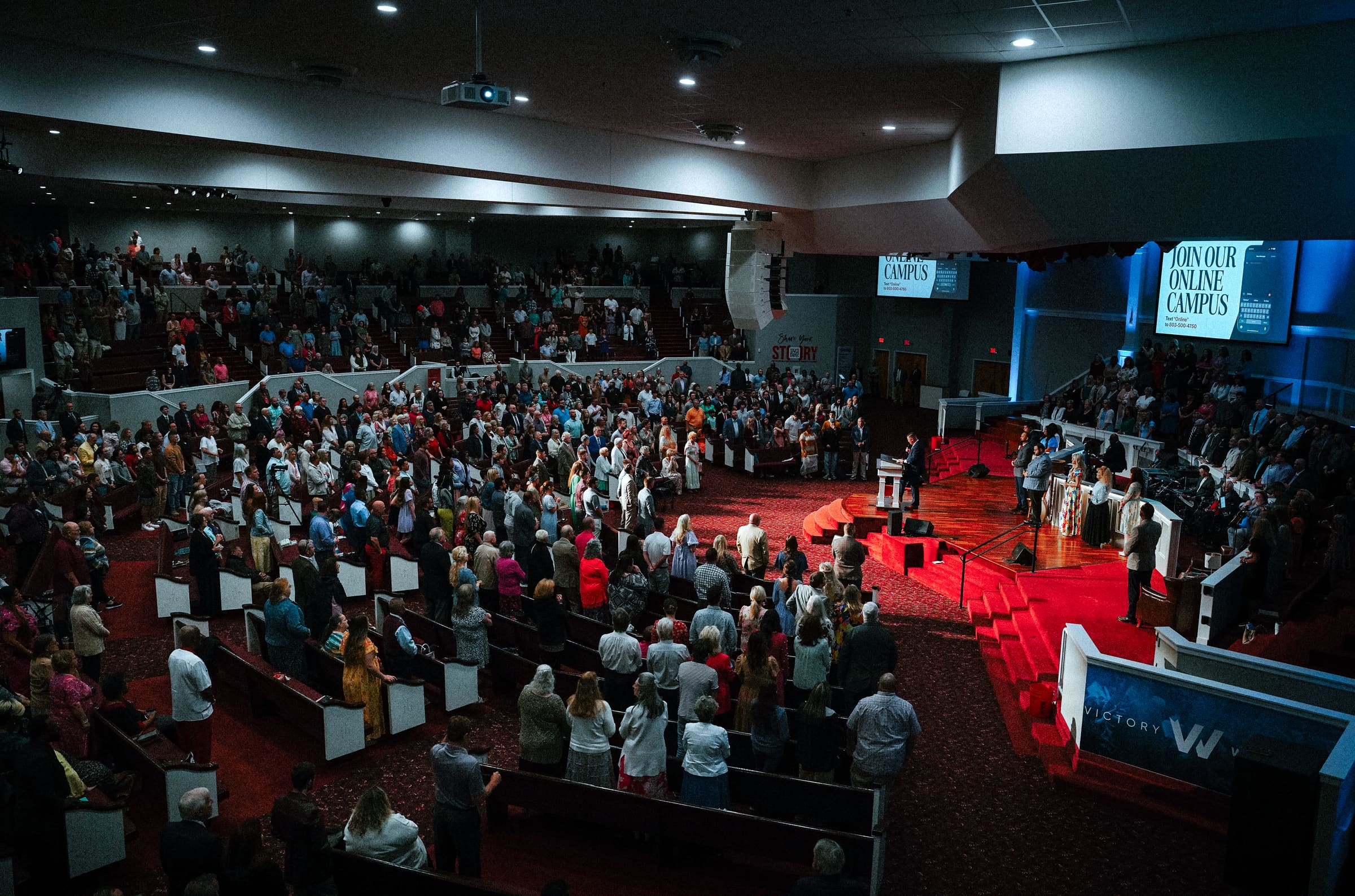 The Victory Baptist auditorium full, the congregation standing during a Sunday service
