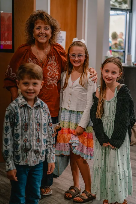 A leader with her arms around three children in the lobby