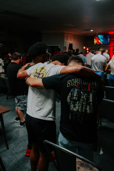 Young adults with their arms around each other during a service