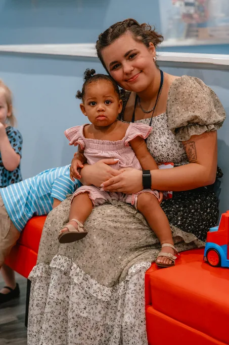 A mom holding her toddler on her lap in the nursery