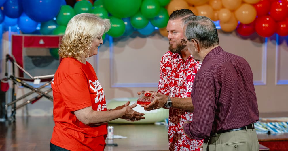 Mrs. Dona McBride in her red Dream Team shirt receiving her award on the Victory stage at the Dream Team Rally