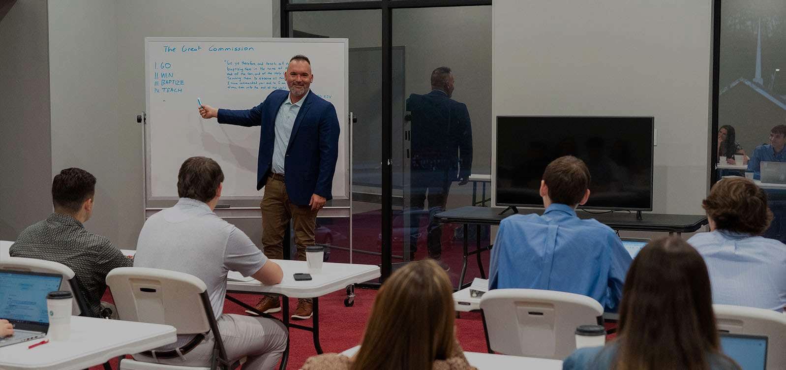 A Victory Baptist College class in session, the instructor at the whiteboard and students at their laptops