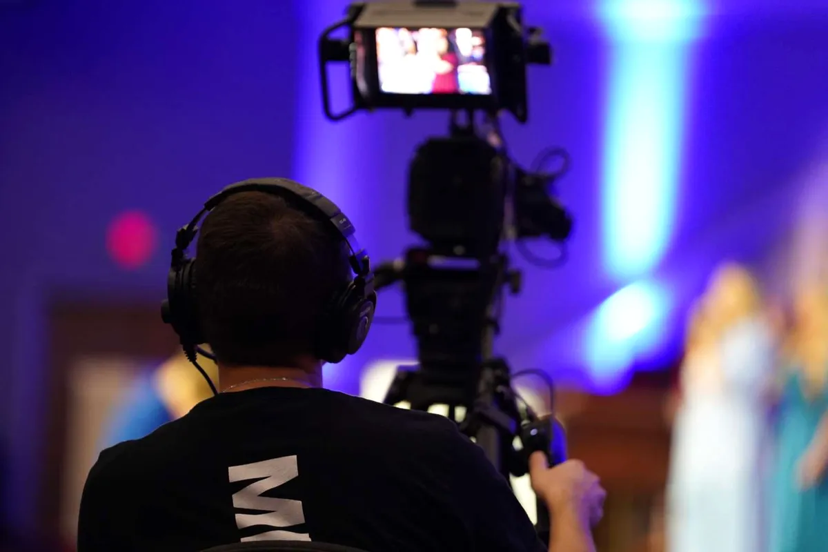 A camera operator in headphones filming a service