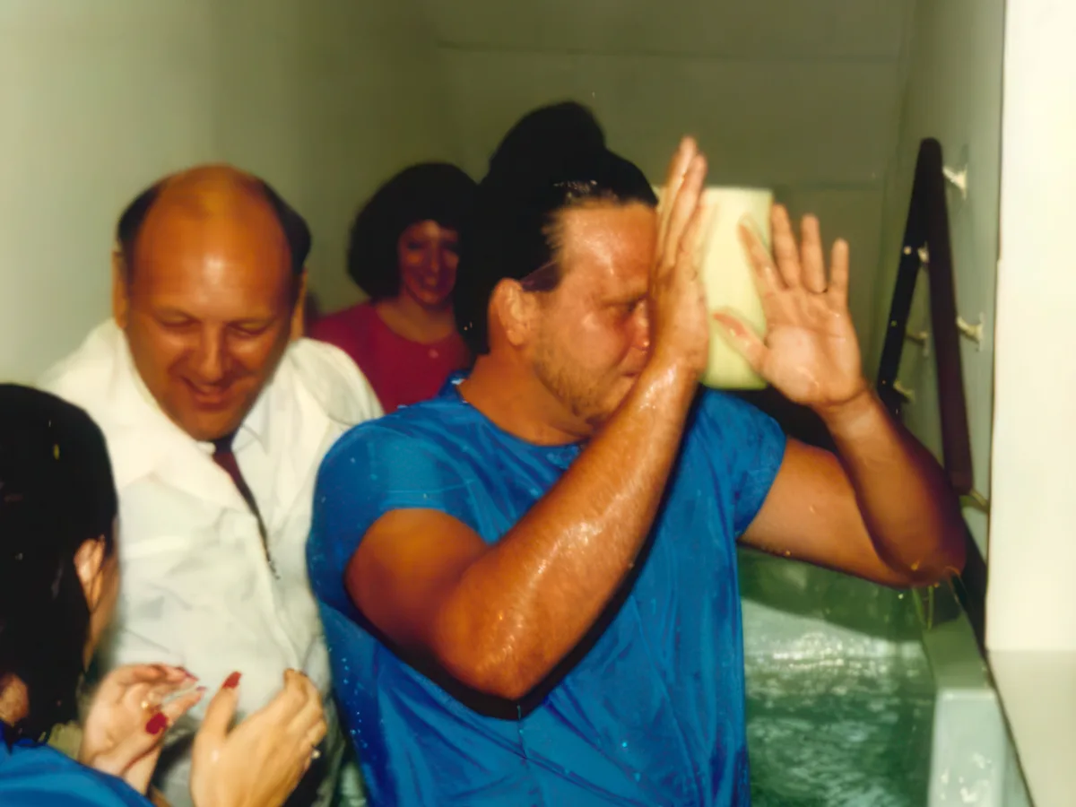 Dr. R. Larry Brown laughing as he baptizes a man in the church baptistry