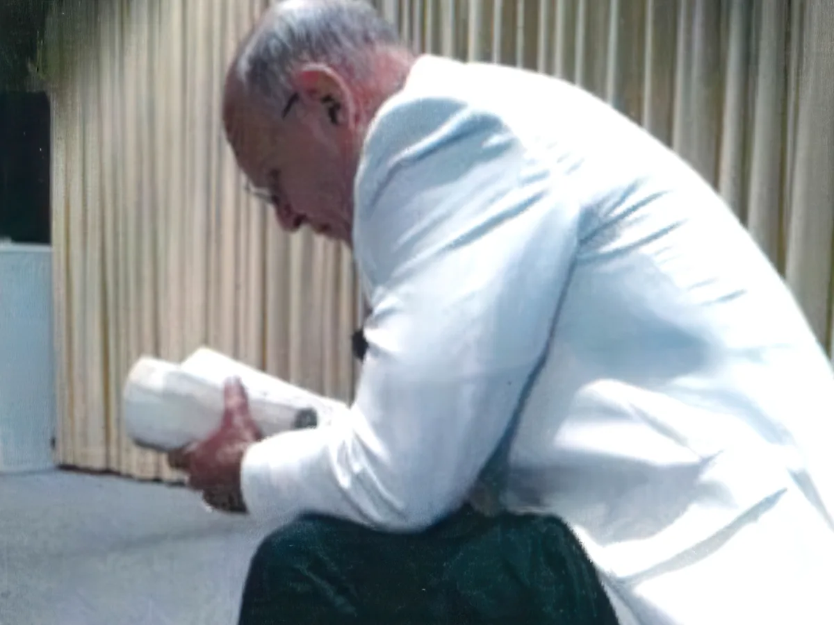 Dr. Brown seated with his head bowed over his open Bible in prayer