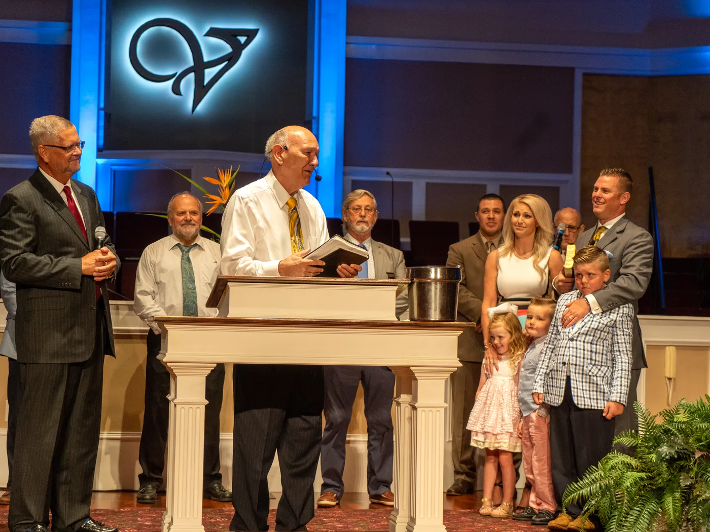 Dr. R. Larry Brown speaking at the pulpit with Pastor CT and his family beside him