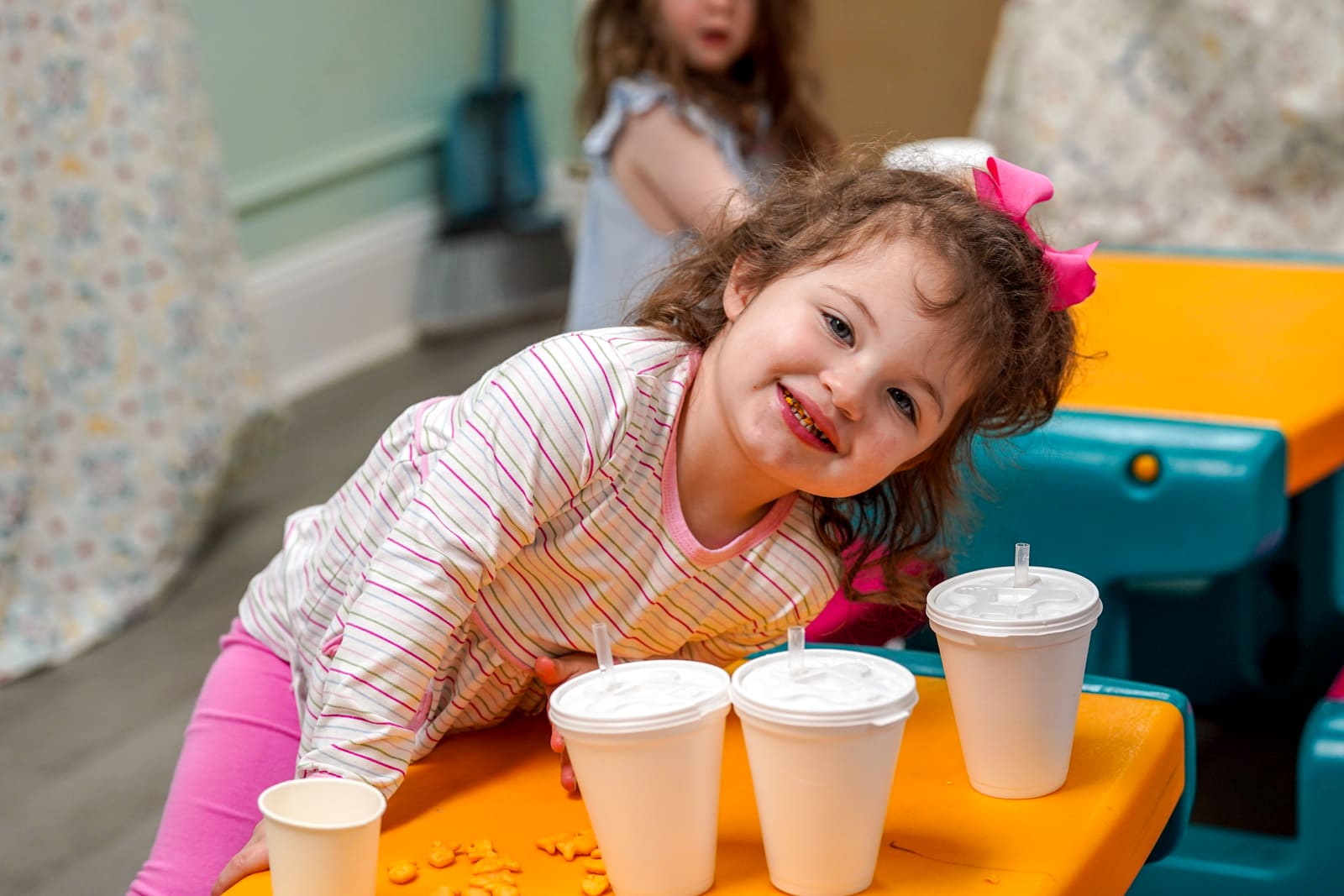 A little girl smiling at the snack table in the kids wing
