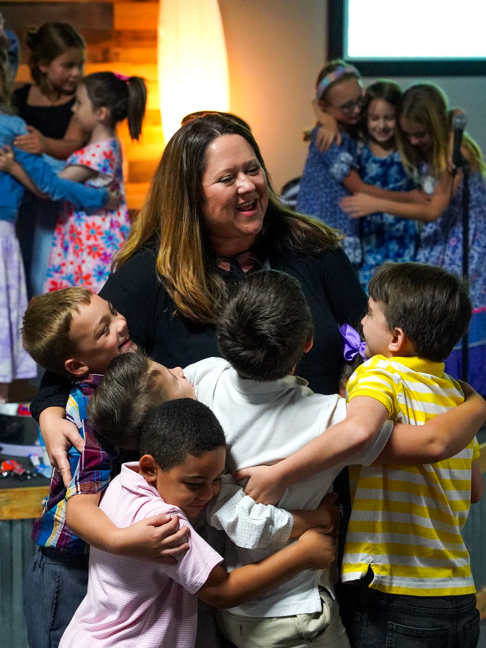 Five kids wrapping their kids ministry leader in a group hug after church