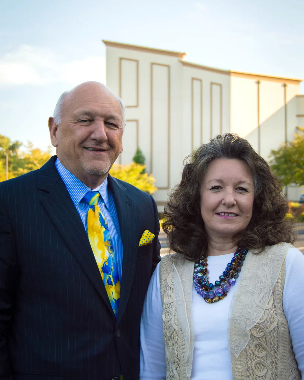 Dr. R. Larry Brown and his wife smiling in front of the Victory Baptist Church building