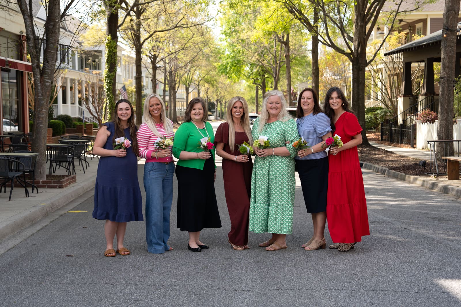 Ladies’ Ministry members holding flowers together on a tree-lined street