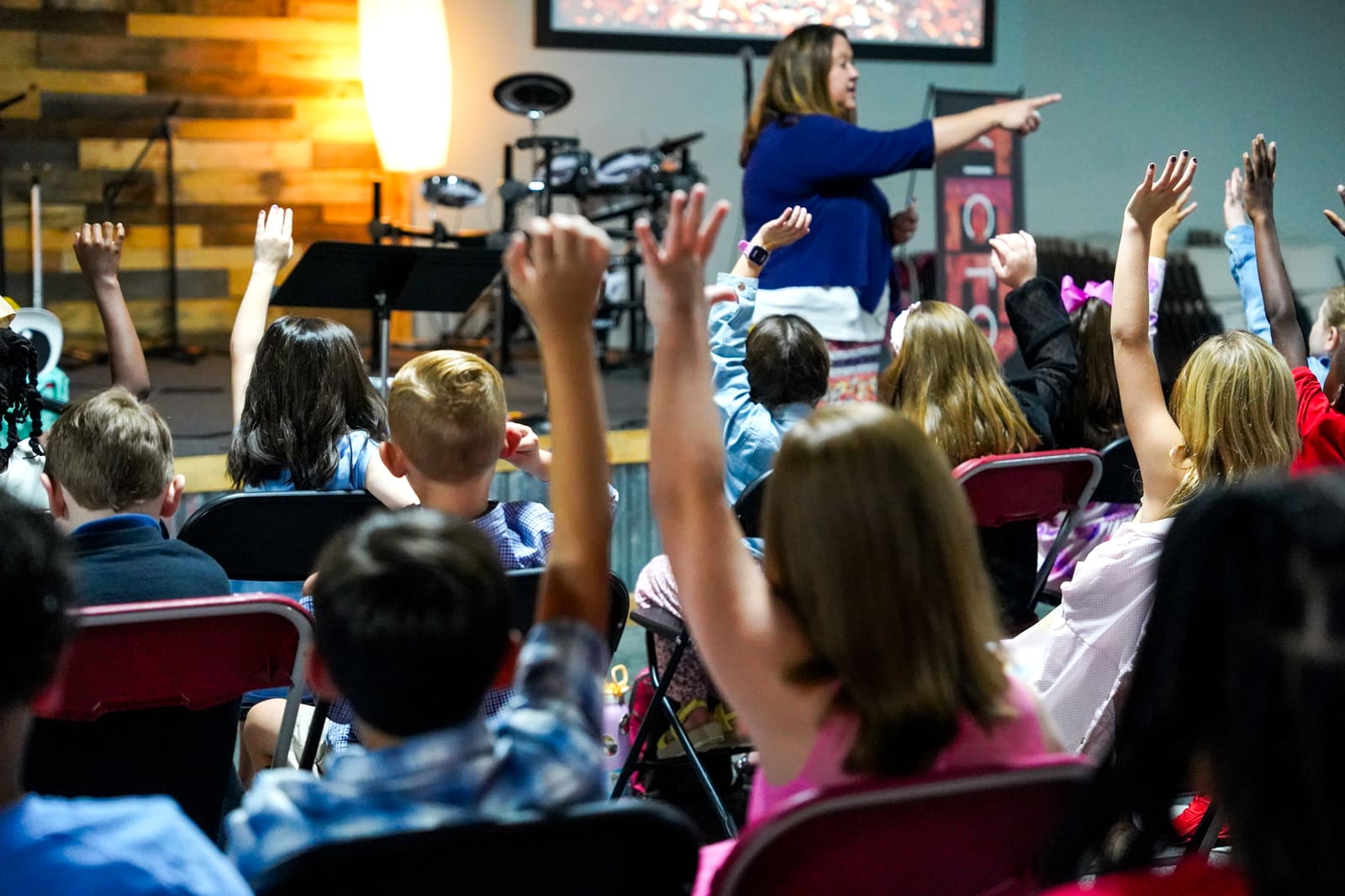 Cheryl Hampton leading a room of Victory Kids with their hands raised