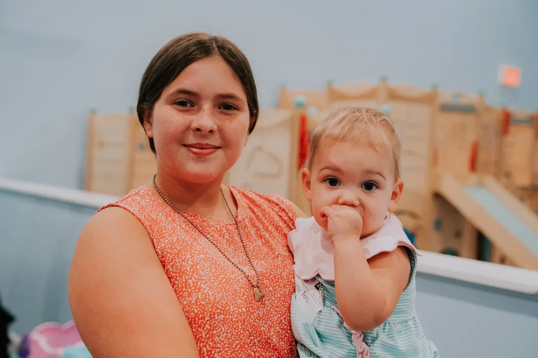 An older girl holding a baby in the Victory Nursery
