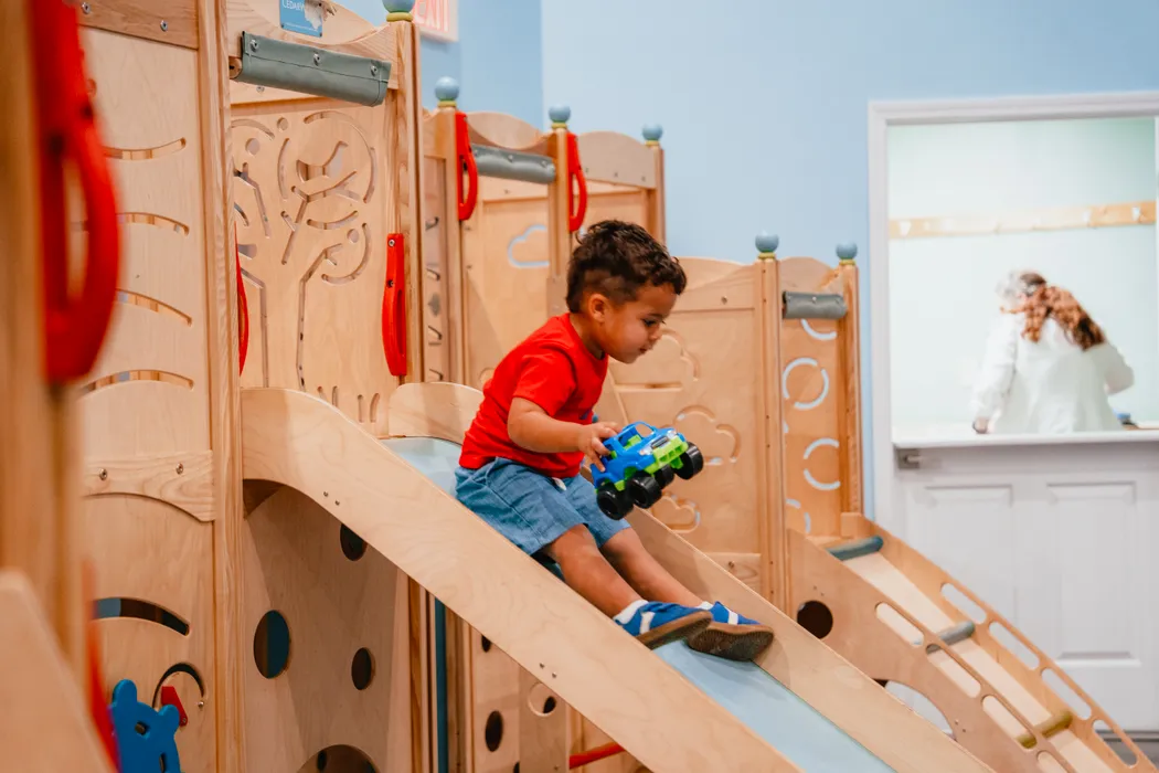 A boy riding the slide in the Victory Kids play area