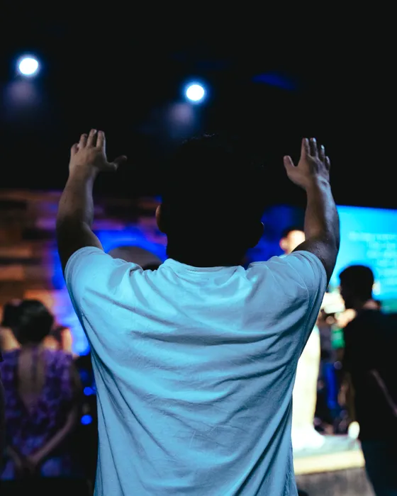 A teen with both hands raised during worship