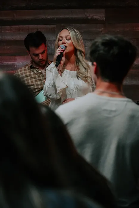 A young woman singing at a Victory Young Adults service