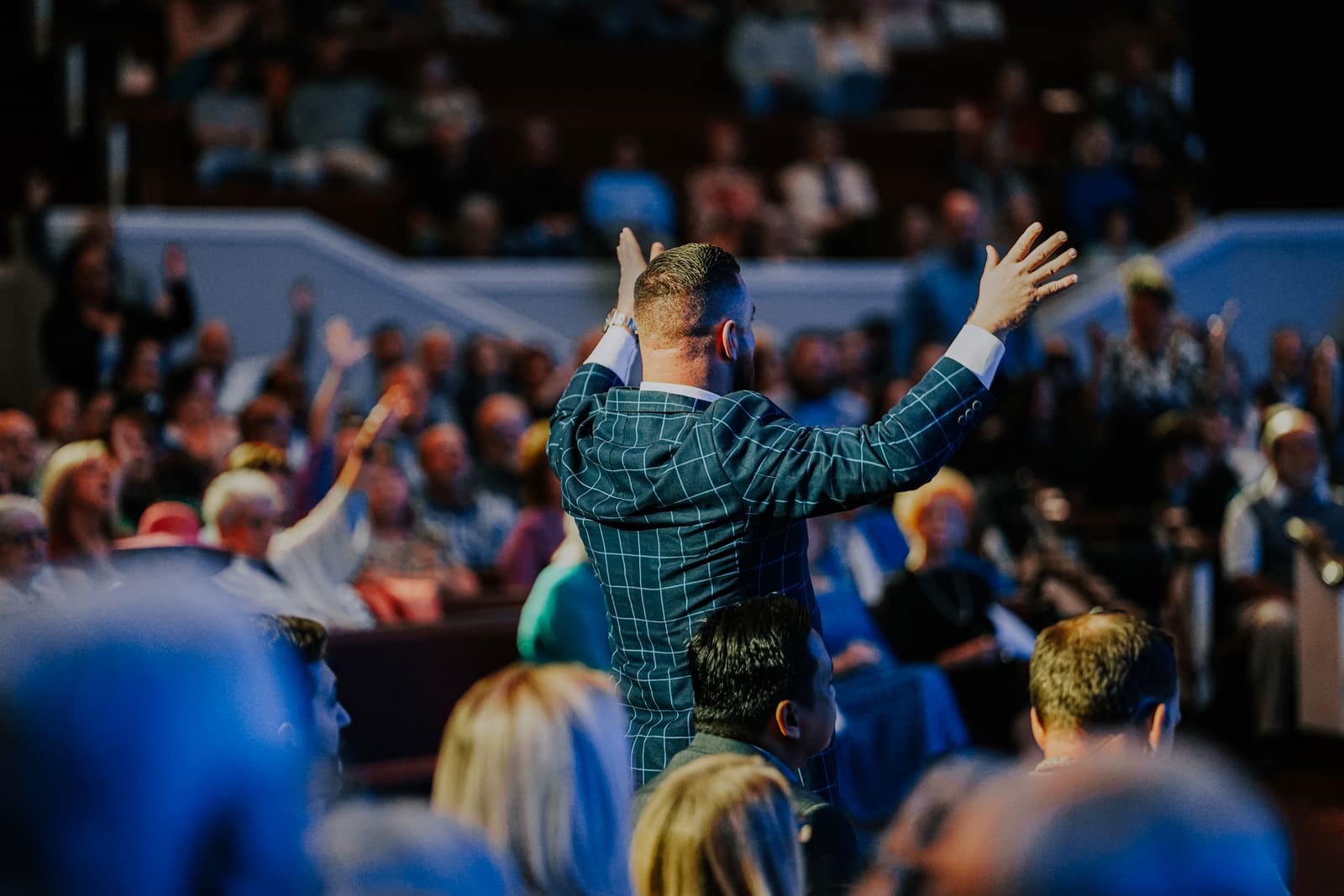 Pastor CT waving to a full sanctuary from the platform on a Sunday