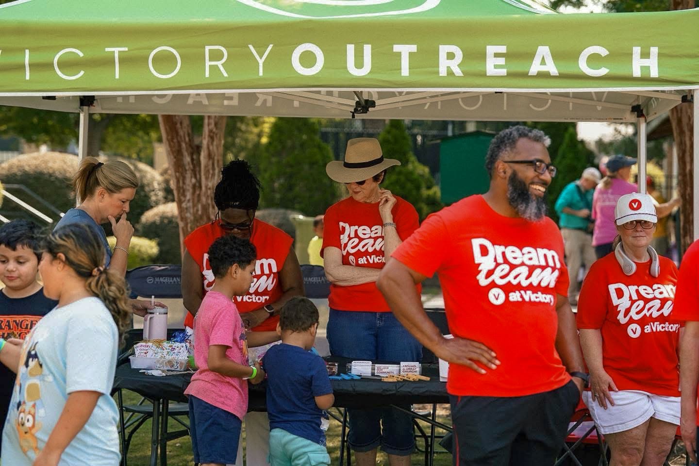 Dream Team members serving families at the table under the Victory Outreach tent