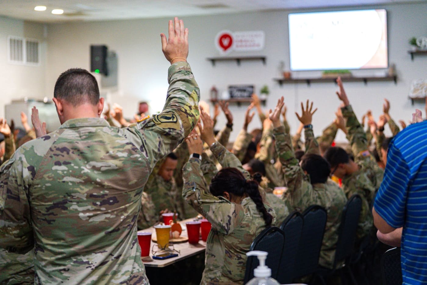 Soldiers and members with their hands raised in worship at a Fort Gordon gathering
