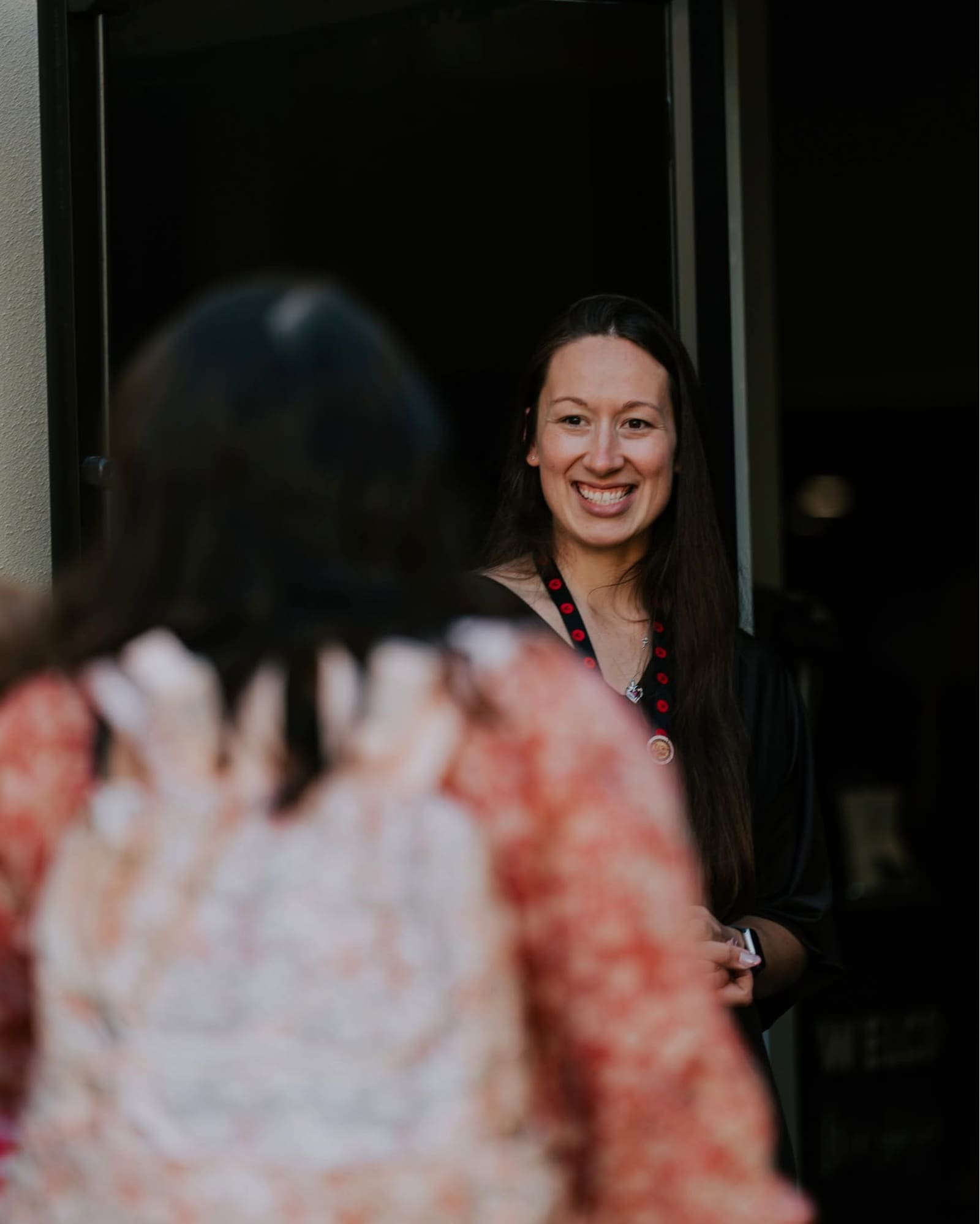 A greeter smiling in the entrance doorway as a guest arrives on a Sunday morning