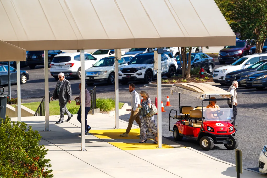 Greeters and a golf cart meeting cars in the Victory parking lot on a Sunday morning