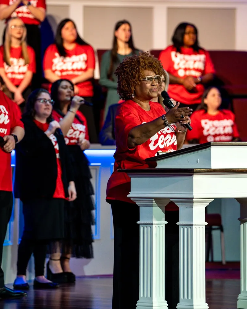 A Dream Team member speaking at the pulpit with the team behind her