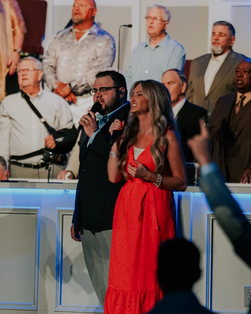 Two vocalists leading worship with the Victory choir behind them