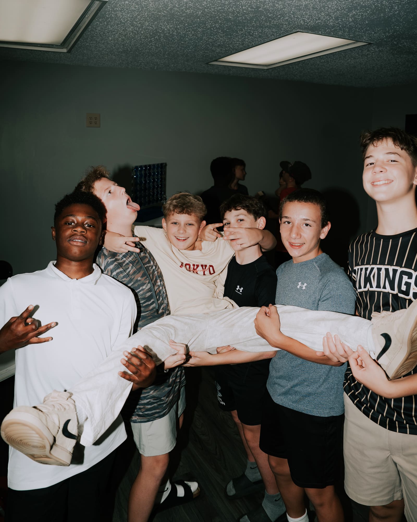 Six teenagers laughing together as they carry a friend at a Victory Teens night