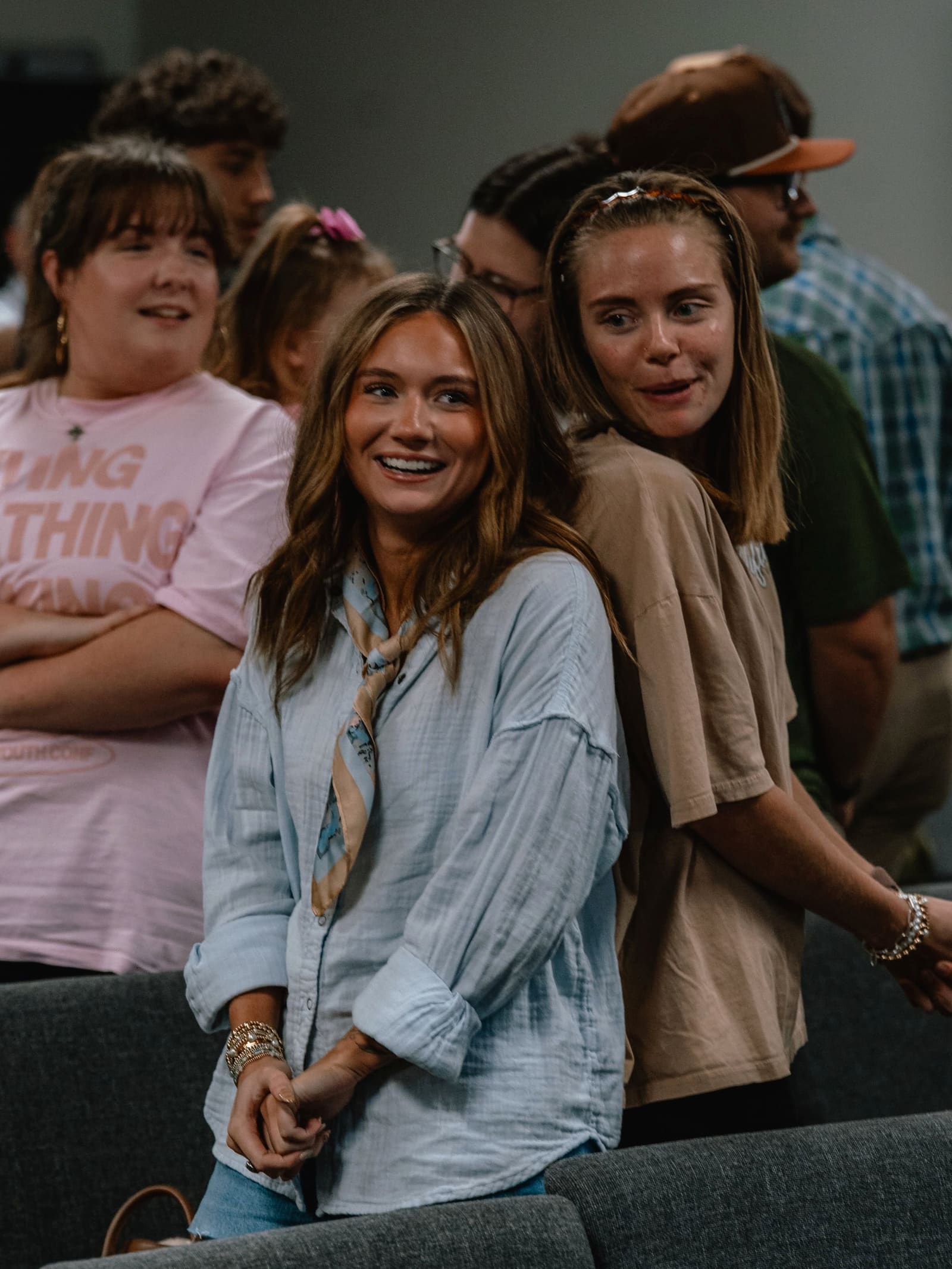 Two college students laughing together between the rows at a service